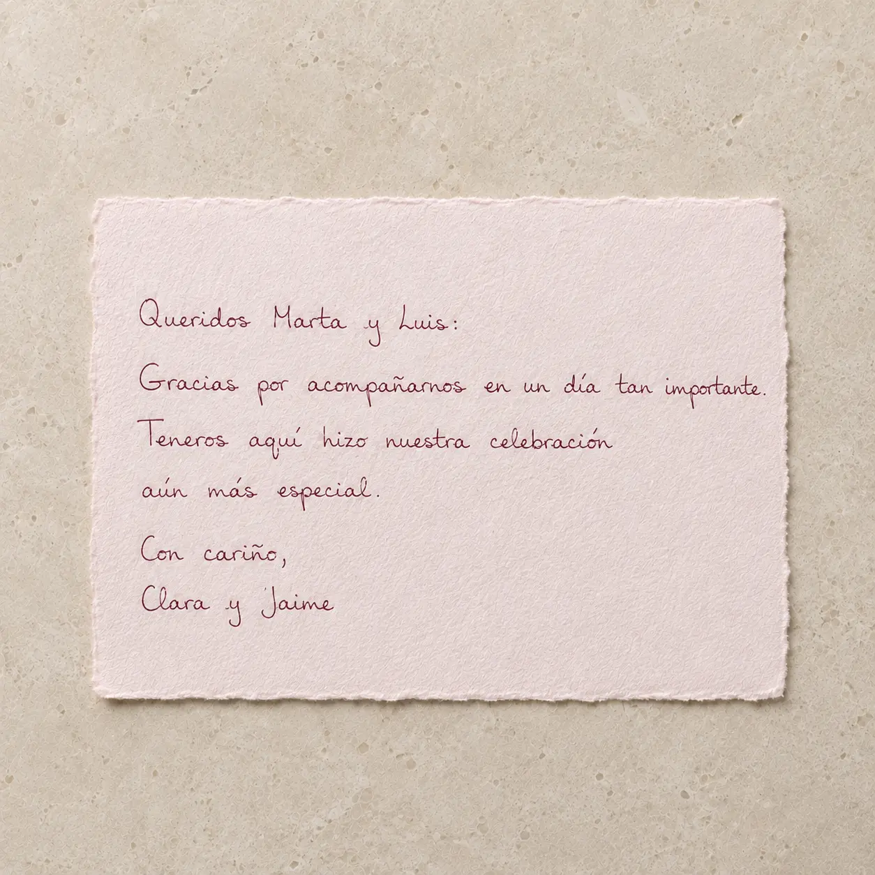 Tarjeta de papel artesanal con nota de agradecimiento de boda escrita con pluma en tinta granate.