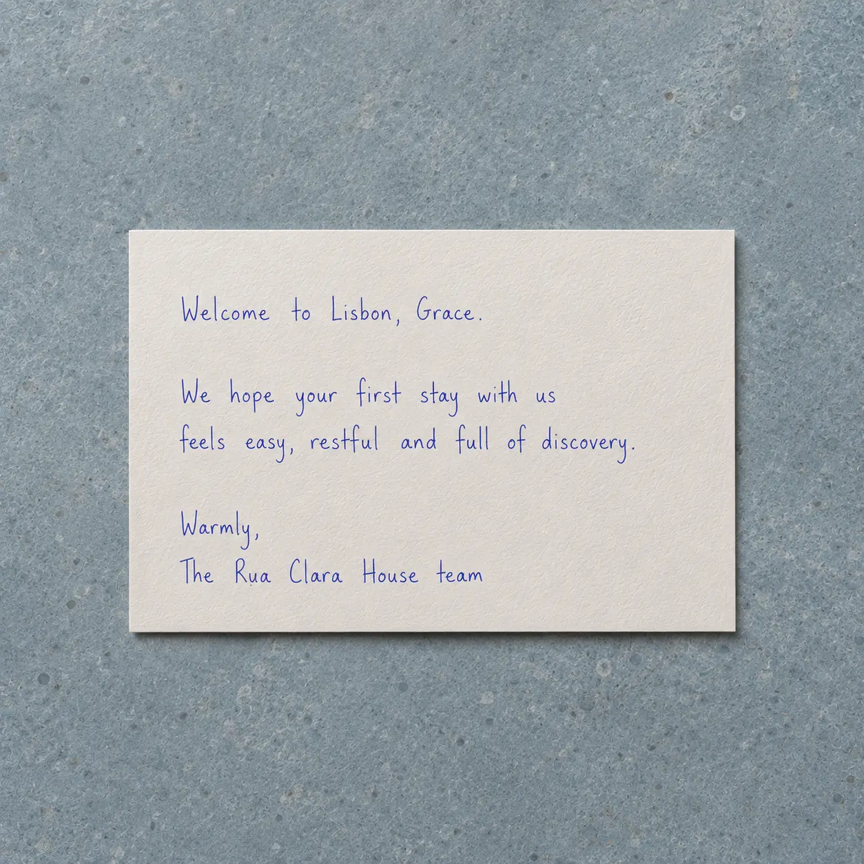 Tarjeta de bienvenida de hotel en inglés escrita con bolígrafo azul sobre papel crema.